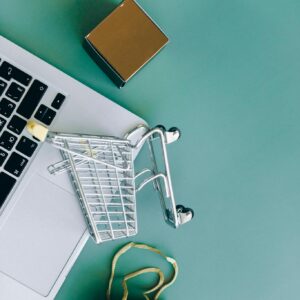 Flat lay of a laptop, shopping cart, and parcels symbolizing online shopping and ecommerce.