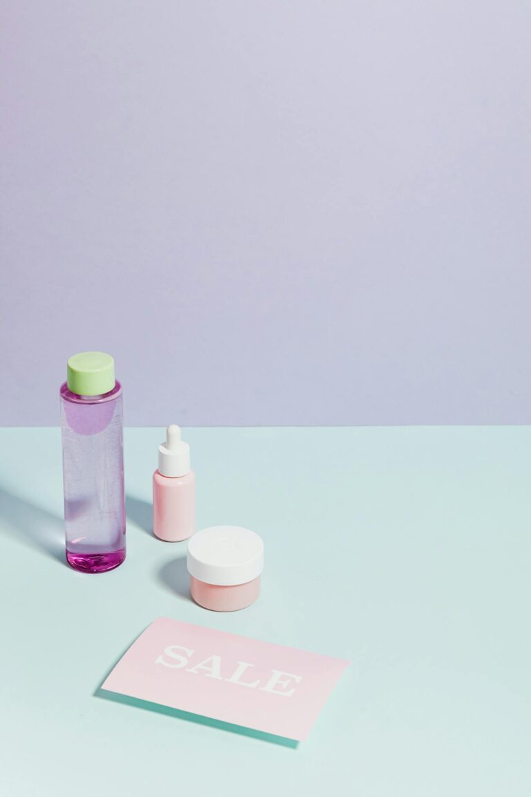 Flat lay of skincare products and sale sign on pastel backdrop, ideal for promotions.