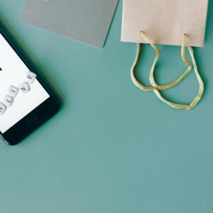 Illustration of online payment with smartphone, credit card, and shopping bag on mint background.