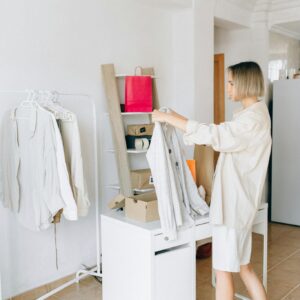 Woman sorting garments in a modern apartment, showcasing a clean, minimalist lifestyle.